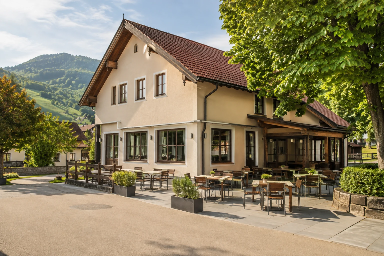 Österreichisches Gasthaus mit heller Fassade, leerer Terrasse und grünen Hügeln